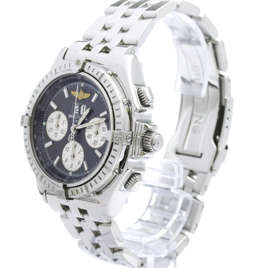 A silver stainless steel wristwatch with a black dial, featuring three subdials, a rotating bezel, and a matching steel link bracelet, displayed on a clear stand against a white background.