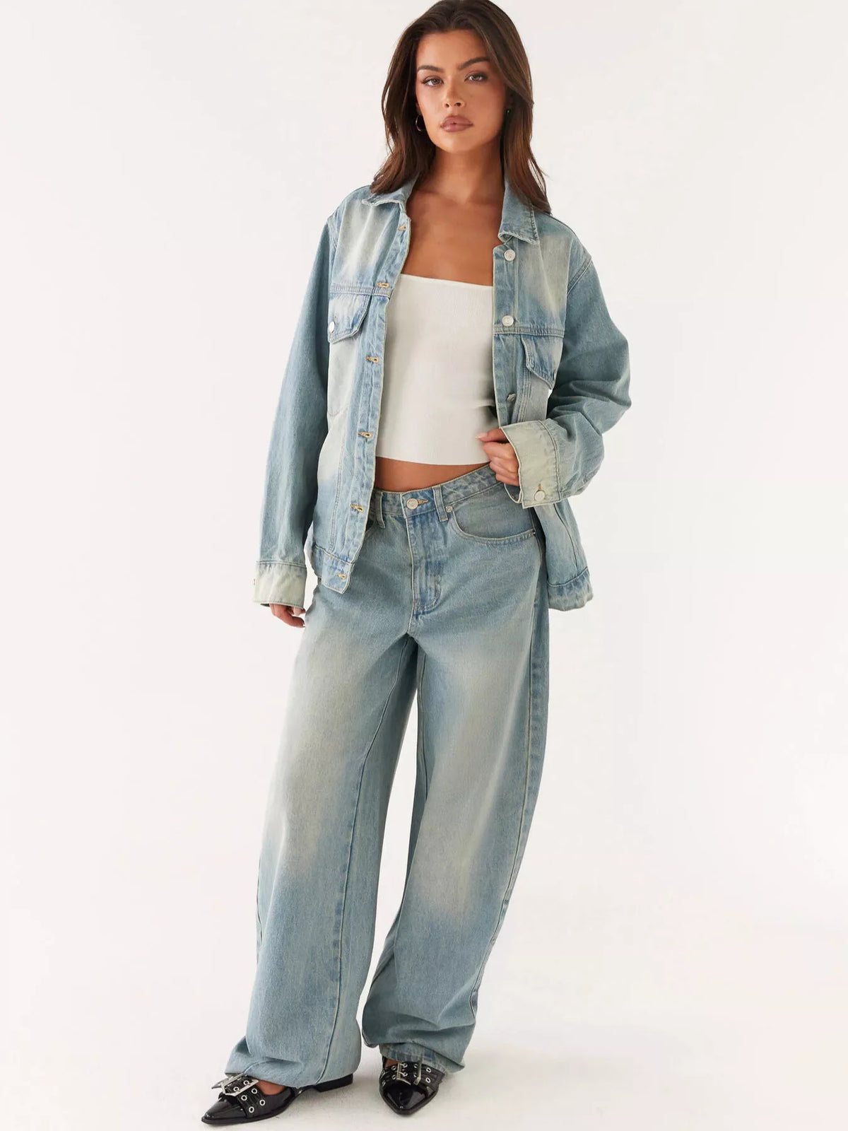 Woman wearing a light blue denim jacket and jeans on a white background