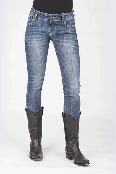 Blue jeans worn by a person with black cowboy boots on a white background