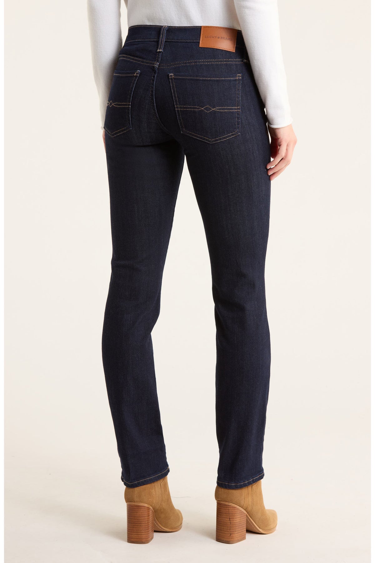 Person wearing dark blue jeans with a plain background