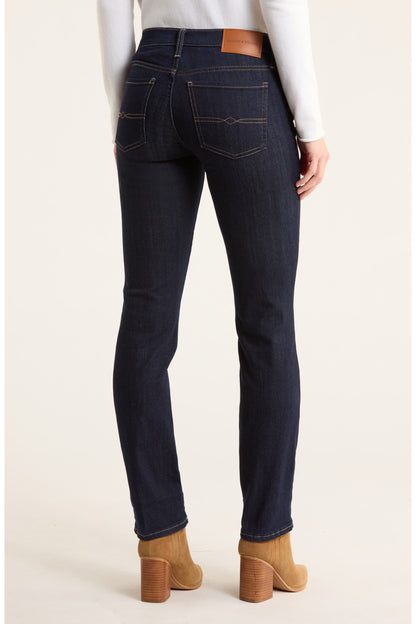 Person wearing dark blue jeans with a plain background