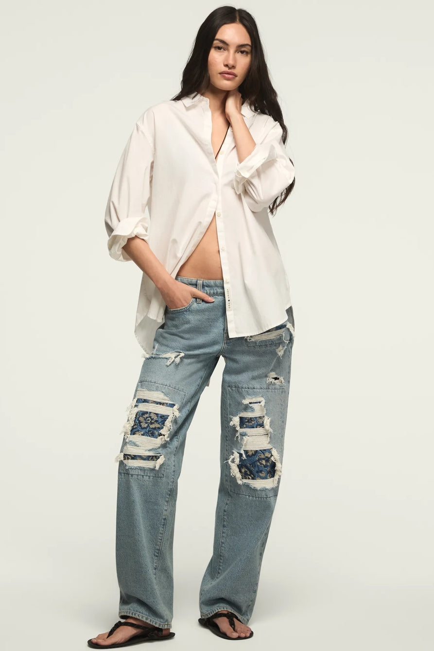Woman wearing a white blouse and distressed blue jeans on a white background