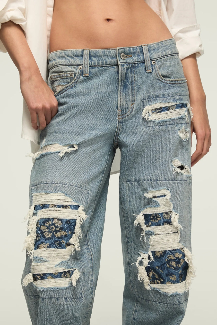Ripped blue jeans worn by a person on a white background