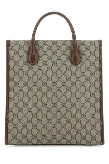 Designer tote bag with patterned fabric and brown leather handles on a white background