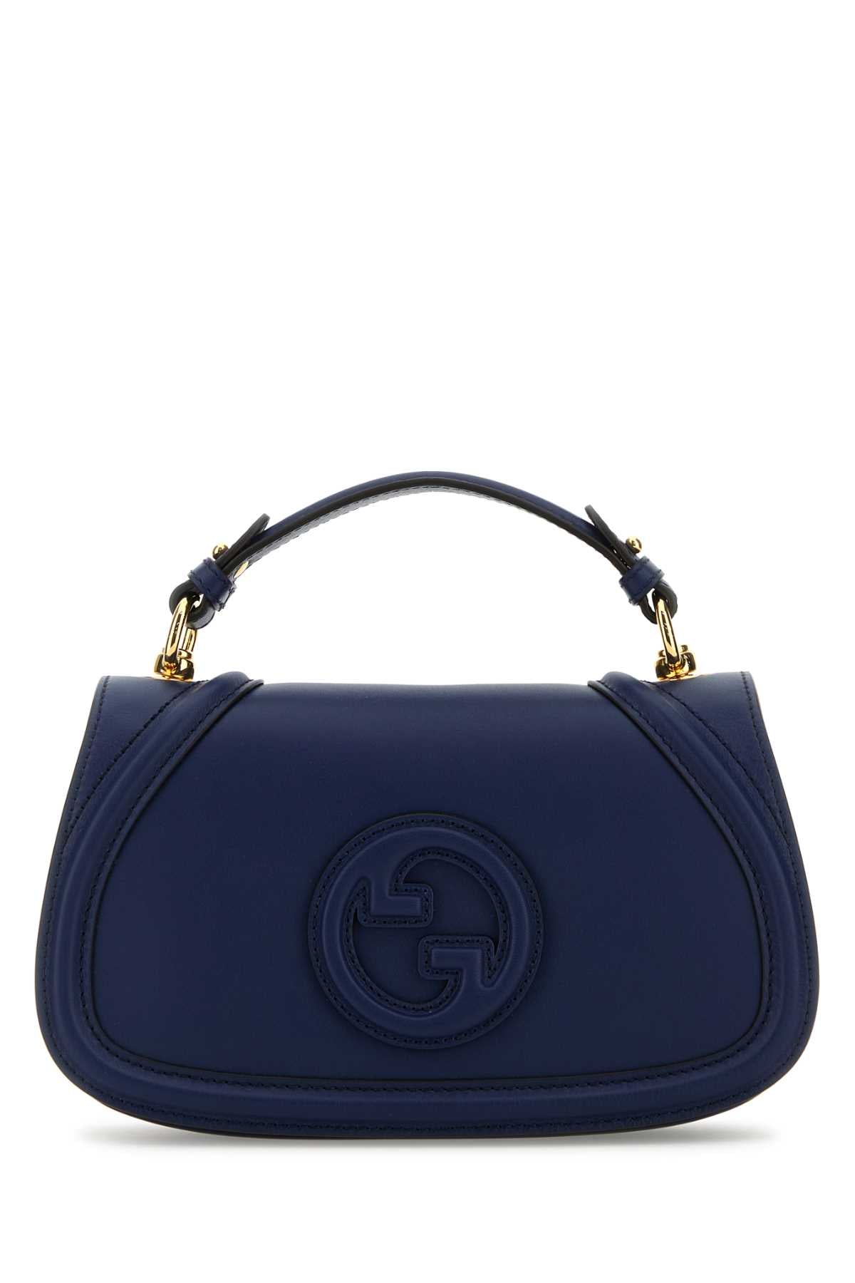A navy blue leather handbag with a top handle and gold-tone hardware, featuring an embossed circular interlocking G logo on the front, set against a plain white background.