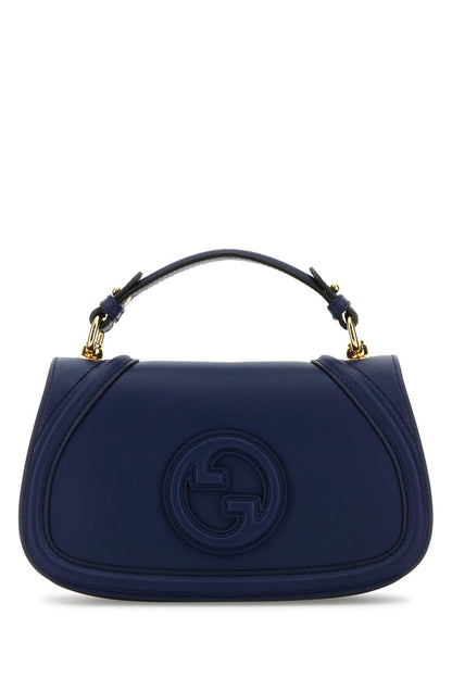 A navy blue leather handbag with a top handle and gold-tone hardware, featuring an embossed circular interlocking G logo on the front, set against a plain white background.