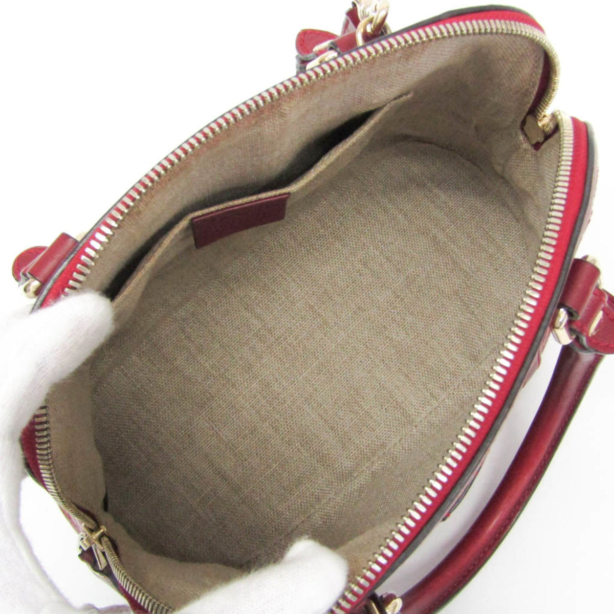 Close-up of a handbag with red exterior and beige interior on a white background