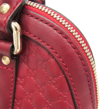 Close-up of a red leather handbag with gold accents