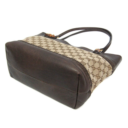 A vintage Gucci handbag in brown leather and beige GG Supreme canvas, shown from a three-quarters angle on a white background.