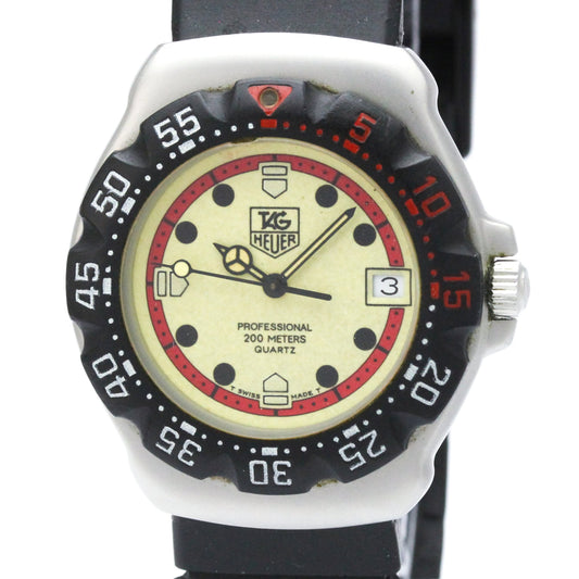 A vintage TAG Heuer Professional 200 meters quartz watch with a silver-tone case, black bezel, black strap, and a cream-colored dial featuring red accents and black markings.