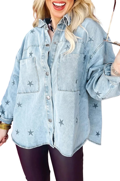 A woman wearing an oversized light-wash blue denim shirt jacket with dark gray star prints, paired with dark leggings, in a festive holiday-themed store setting.