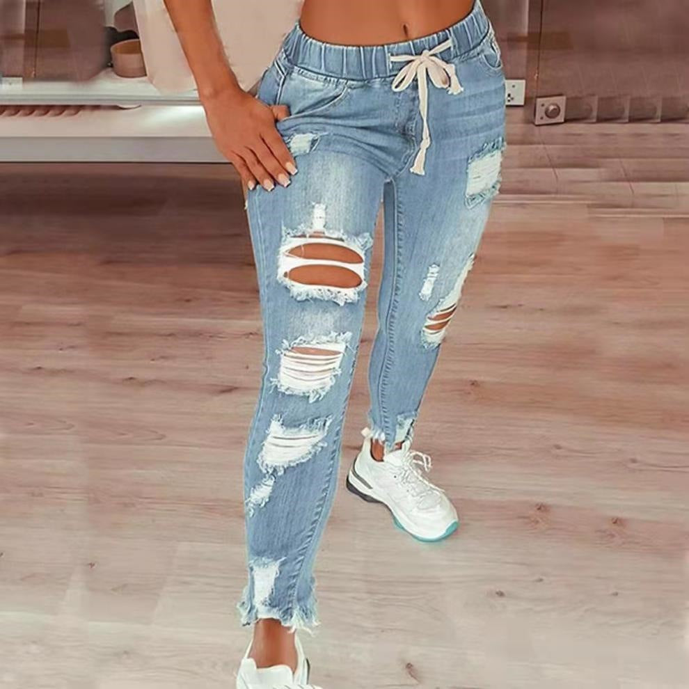 Person wearing distressed blue jeans on a wooden floor.