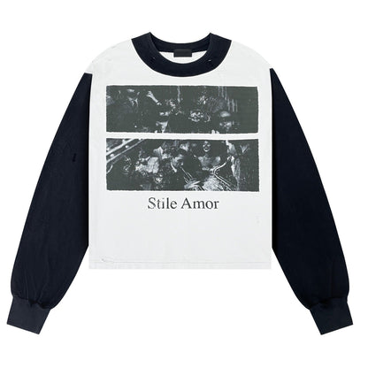 A long-sleeve crop top sweatshirt with a white body, dark navy collar and sleeves, and a black-and-white graphic print on the front featuring the text 'Stile Amor'.