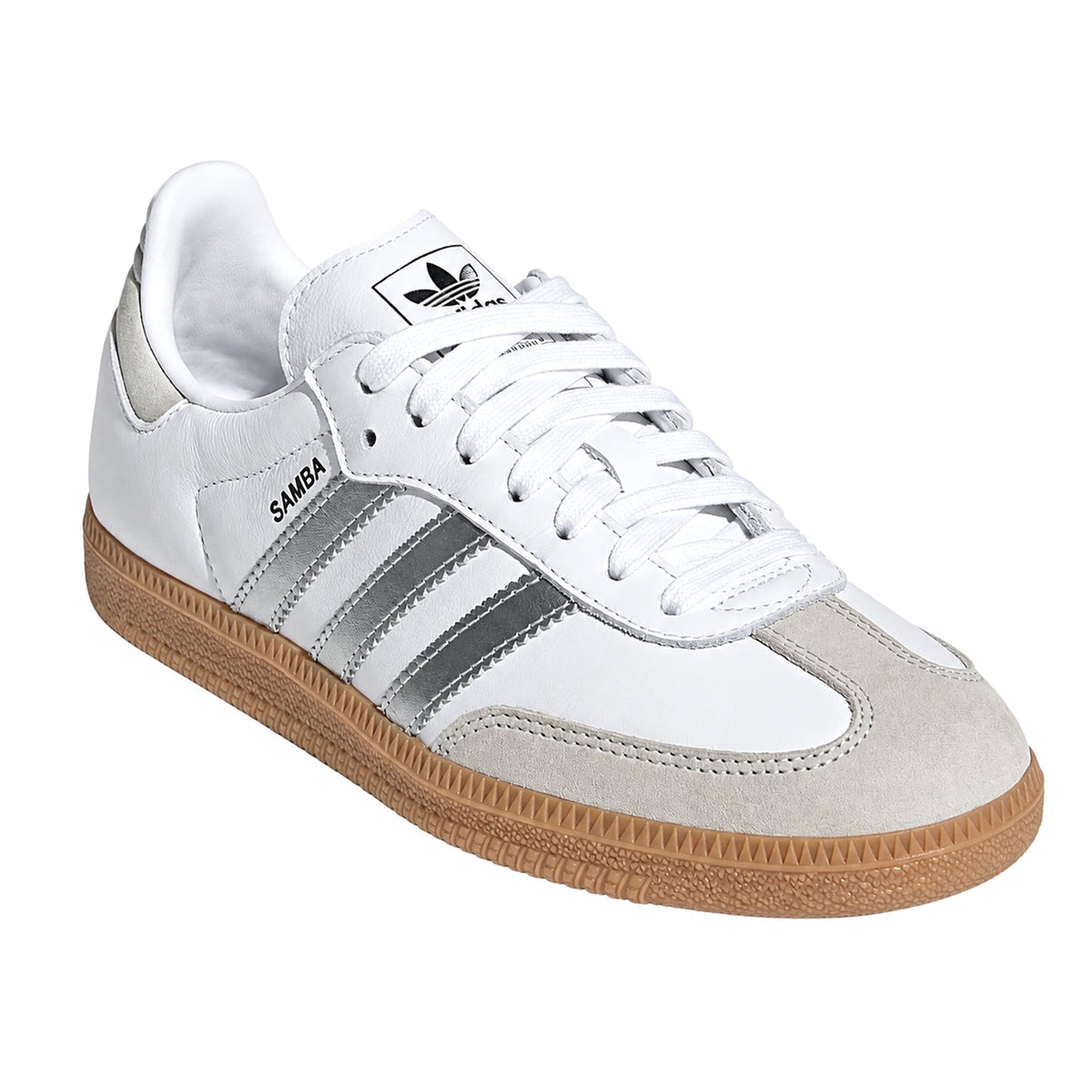 A white Adidas Samba sneaker with metallic silver stripes, a light gray suede toe cap, and a brown gum sole, shown on a plain white background.