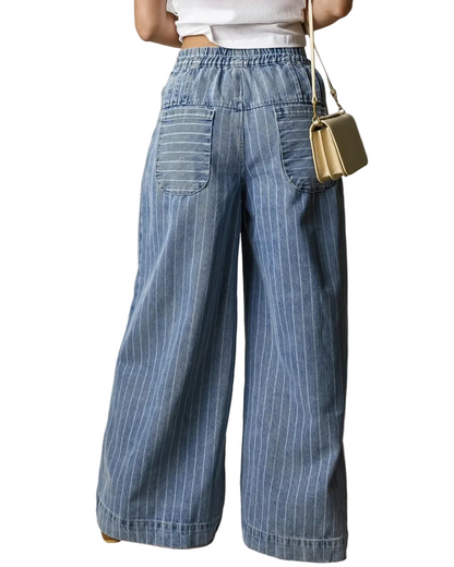 Person wearing blue striped wide-leg pants with a gold handbag on a neutral background