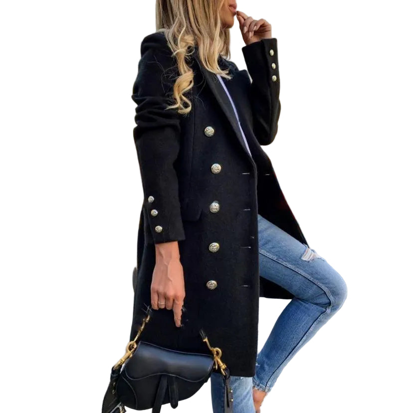 Woman in a black coat with silver buttons and blue jeans standing on a street.