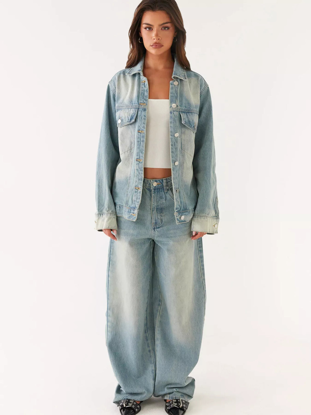 Woman wearing a light blue denim jacket and pants on a white background