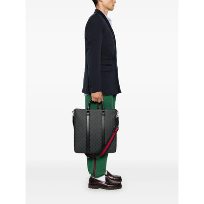 Person holding a black textured briefcase with red accents on a white background