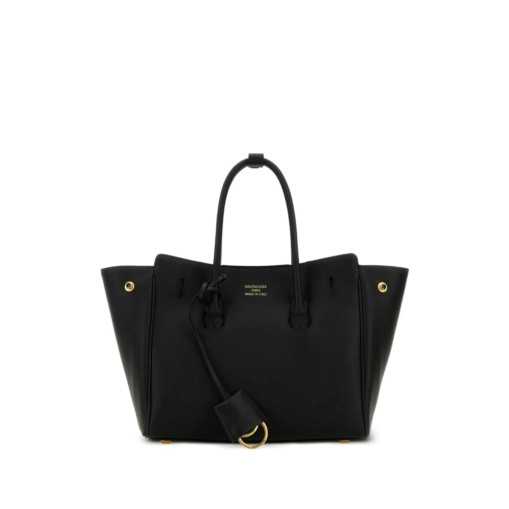 A black leather tote bag with gold-tone hardware, featuring dual top handles, a detachable shoulder strap, and gold lettering on the front that reads 'BALENCIAGA PARIS'.