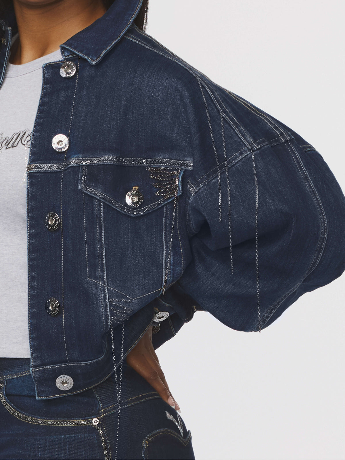 Blue denim jacket with button details on a plain background