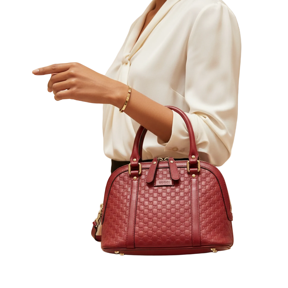A woman in a white blouse holds a burgundy quilted leather handbag with gold-tone hardware in a softly lit boutique setting.