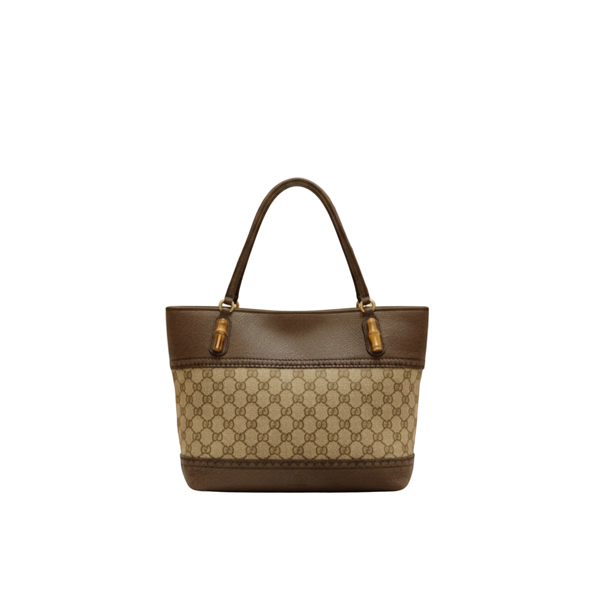 A structured tote handbag with a brown and beige monogram pattern, featuring dark brown leather trim and handles with gold-tone hardware, displayed on a white marble counter in a softly blurred boutique setting.