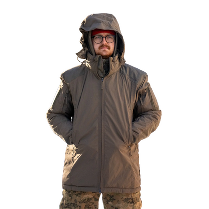 Man wearing a brown winter coat standing in a snowy landscape.