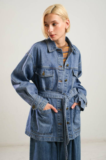 Person wearing a denim jacket with a plain background