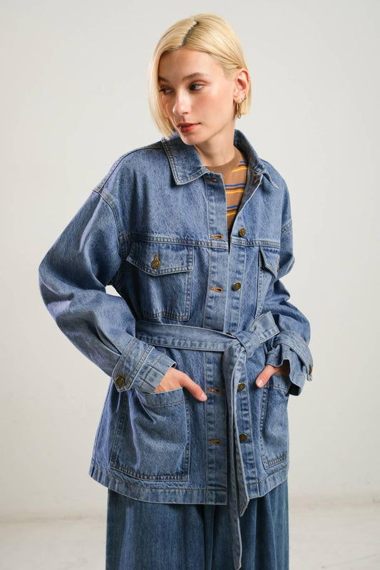 Person wearing a denim jacket with a plain background