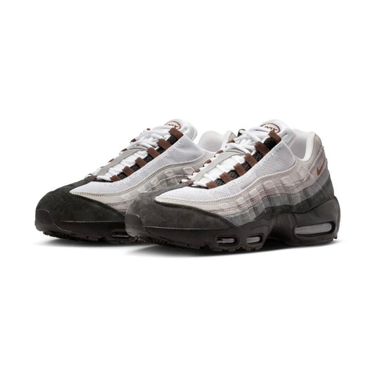 A pair of Nike Air Max 95 sneakers in a white, gray, and brown colorway, featuring a mesh upper, suede toe cap, and gradient midsole, shown against a plain white background.
