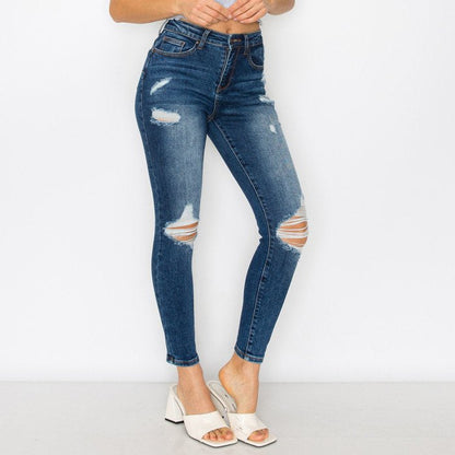 Distressed blue jeans worn by a person on a white background