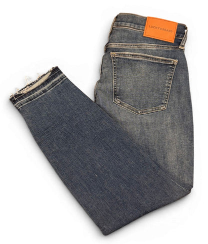 Folded pair of jeans with an orange tag on a white background