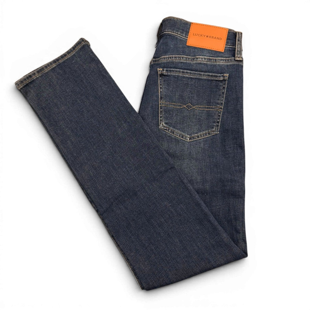 Folded pair of blue jeans with an orange tag on a white background
