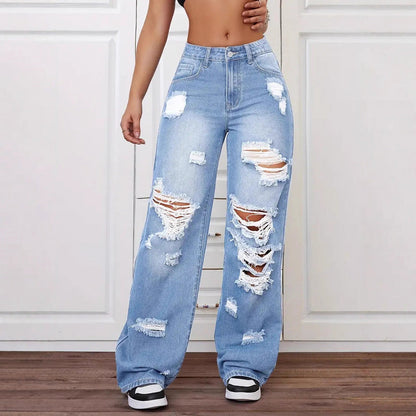 Ripped blue jeans worn by a person on a white paneled wall background