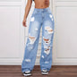 Ripped blue jeans worn by a person on a white paneled wall background