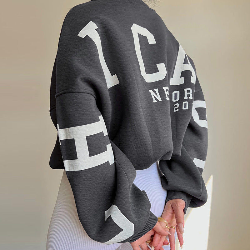 Person wearing a black sweatshirt with white text and graphics on a neutral background