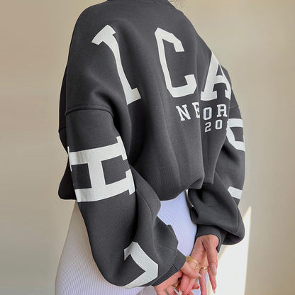 Person wearing a black sweatshirt with white text and graphics on a neutral background