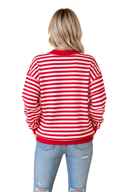 A woman viewed from behind wearing a red and white horizontally striped crewneck sweatshirt and light blue jeans, standing against a solid tan background.