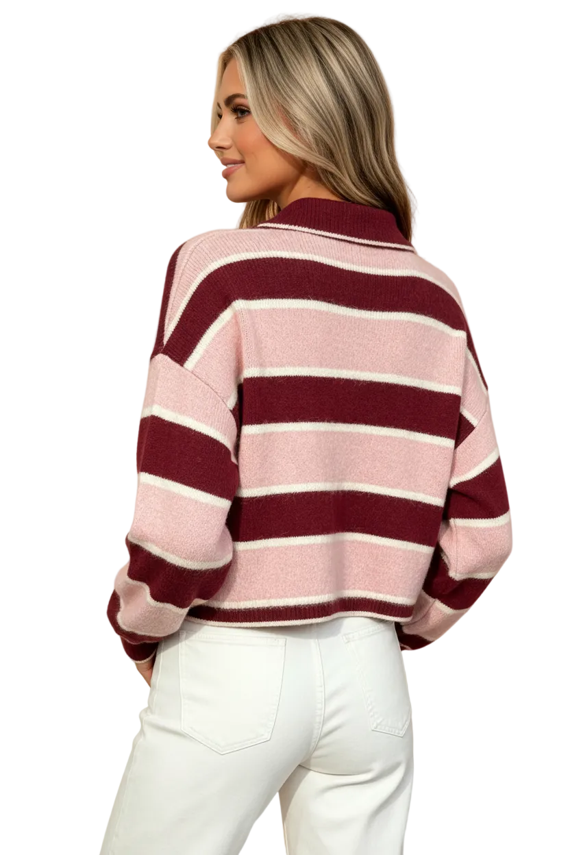 A woman shown from the back wearing a cropped knit sweater with horizontal stripes in dusty pink, burgundy, and off-white, paired with white pants, against a solid peach background.