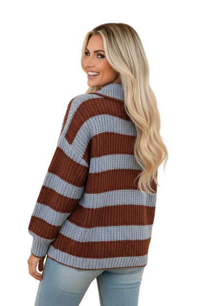 A woman with long blonde hair is shown from the back wearing a chunky knit sweater with horizontal stripes in brown and light blue-gray, paired with light-wash jeans, against a solid peach background.