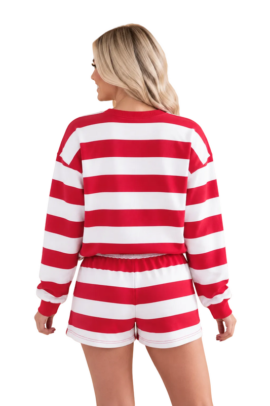 A woman shown from the back wearing a red and white striped long-sleeve crop top and matching striped shorts against a solid tan studio background.