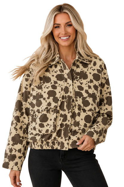 A woman modeling a beige and brown spotted animal print jacket against a solid peach background.