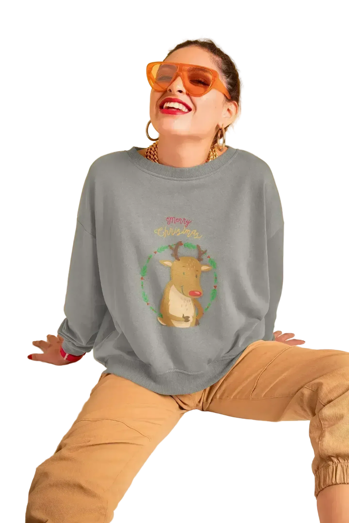 Person wearing a gray sweatshirt with a reindeer graphic and text, sitting on a white surface against a beige background.