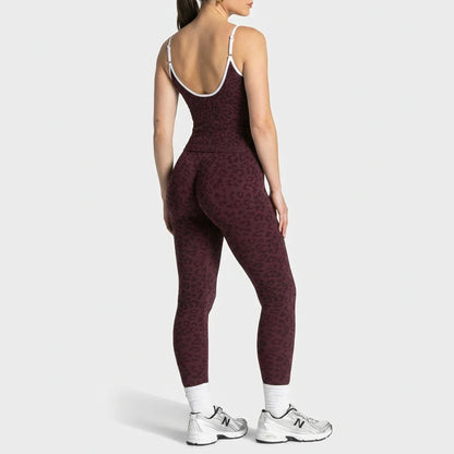 A woman shown from the back wearing a dark burgundy leopard-print activewear set with white trim, white socks, and white New Balance sneakers against a light gray studio background.