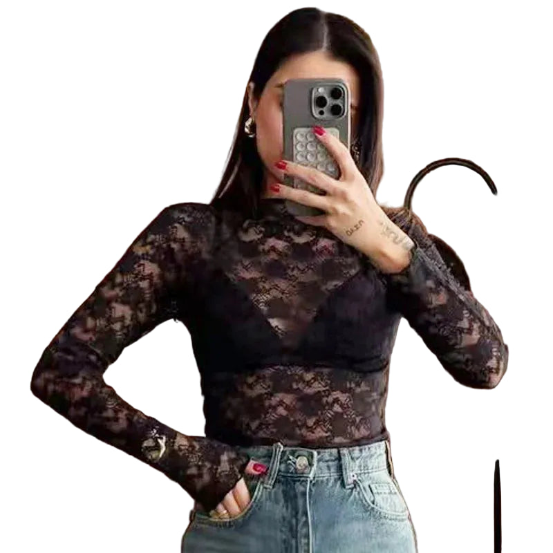 Person wearing a black lace long-sleeve top and blue jeans, taking a mirror selfie.