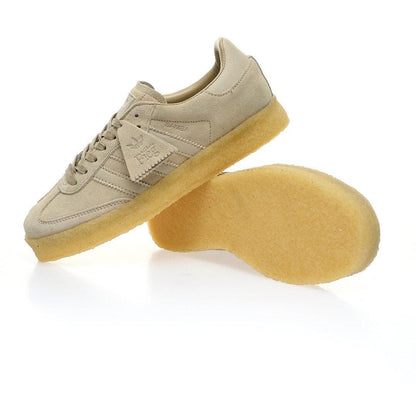 A pair of beige suede sneakers with translucent yellow soles, shown on a clean white background. One shoe is upright, and the other is turned to show the sole.