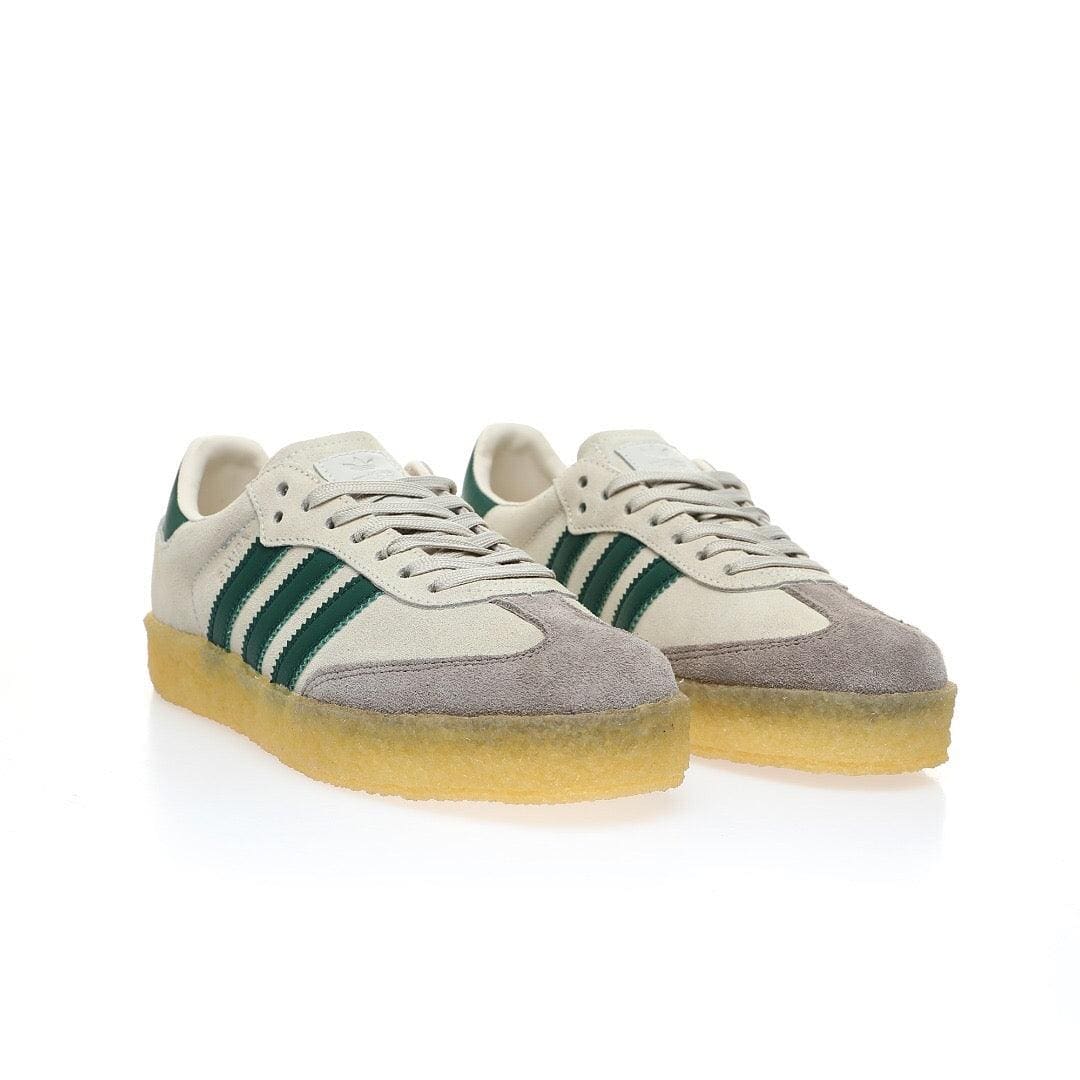 Pair of Adidas sneakers with green stripes on a white background