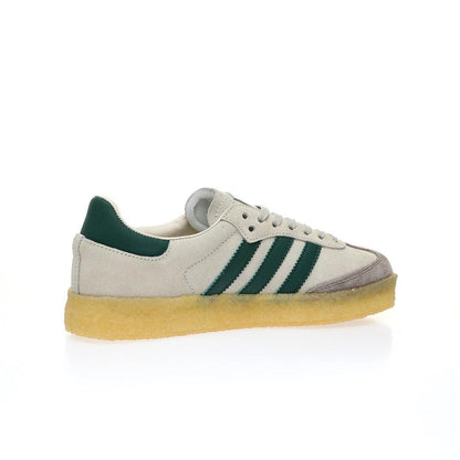 A classic Adidas Gazelle sneaker in off-white suede with dark green stripes and heel tab, featuring a gum sole, shown from a side profile on a white background.