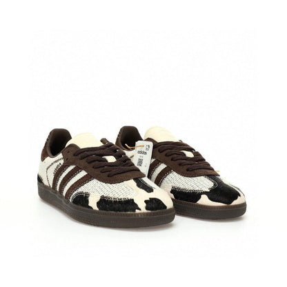Pair of Adidas sneakers with a cow print pattern on a white background