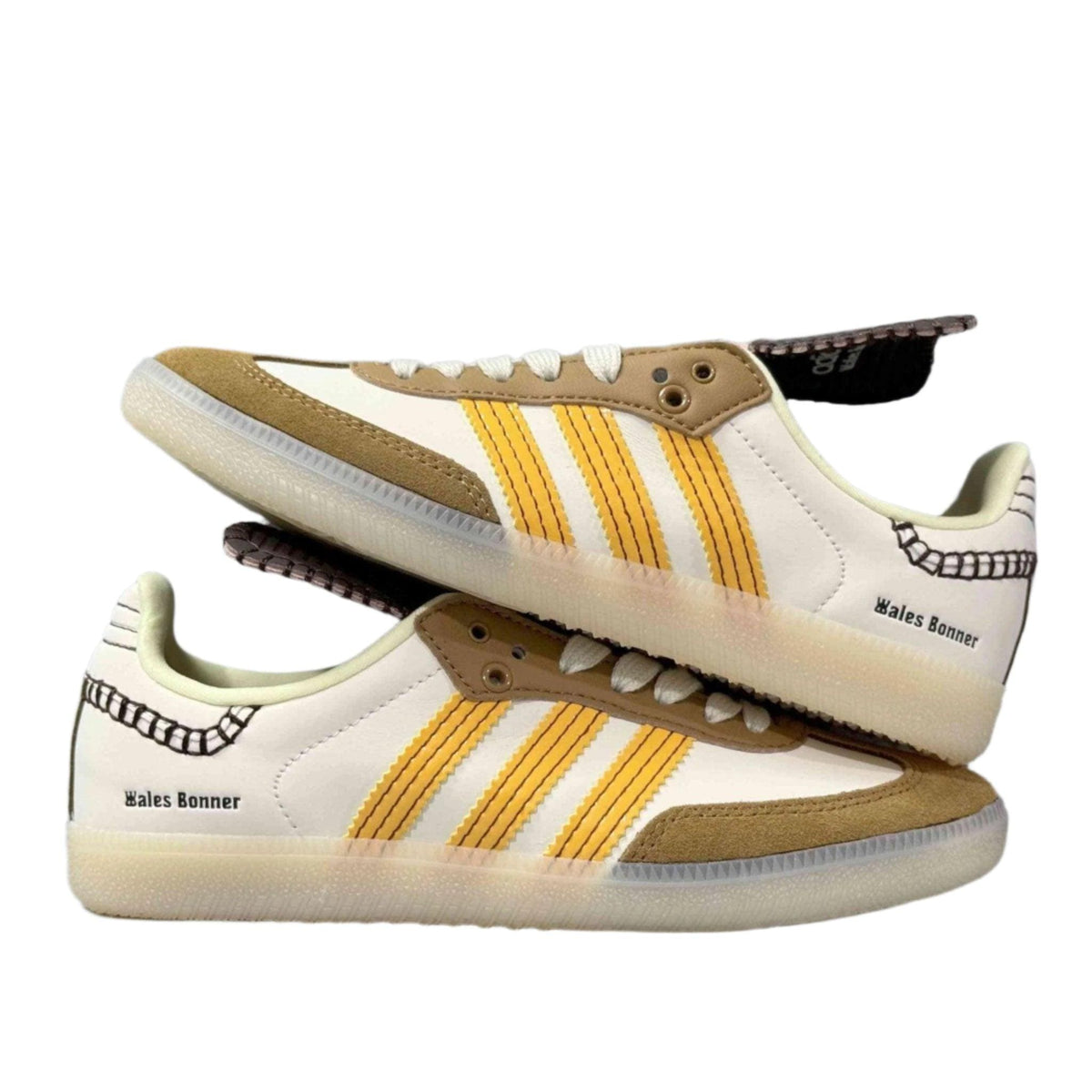 Pair of white sneakers with yellow stripes and brown accents on a white background